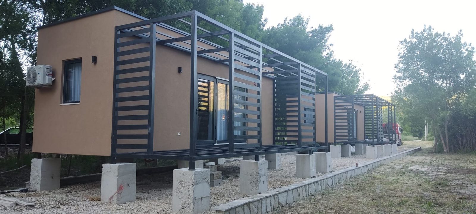 Izvedeni niz modula s crnim čeličnim pergolama na betonskim temeljima